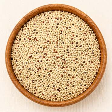 Mixed white, red, and black quinoa seeds filling a round wooden bowl, top-down view