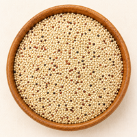 Mixed white, red, and black quinoa seeds filling a round wooden bowl, top-down view