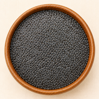 Raw black sabja basil seeds filling a round wooden bowl, top-down view on a cream background